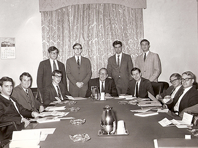 black and white photo of men in suits around a table