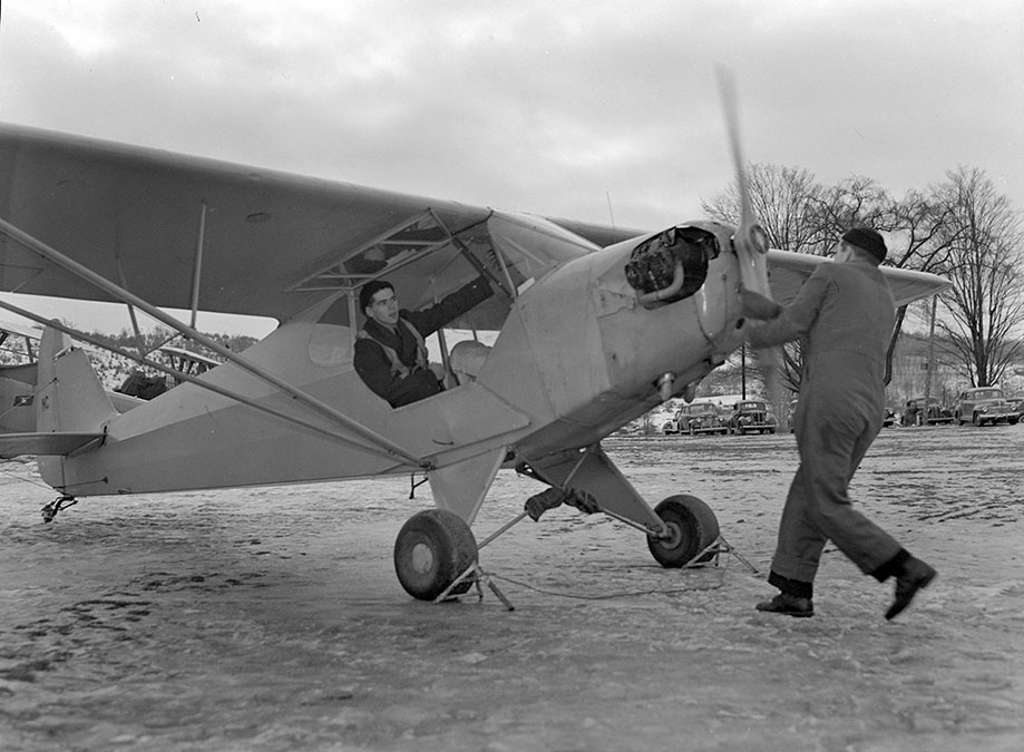 Navy Flight Preparatory School cadet starts airplane by turning propeller, 1944