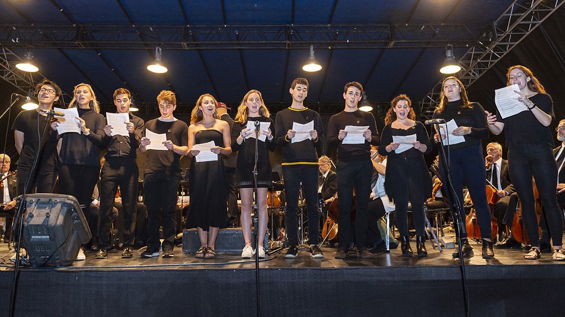 Students sing on stage with Symphoria