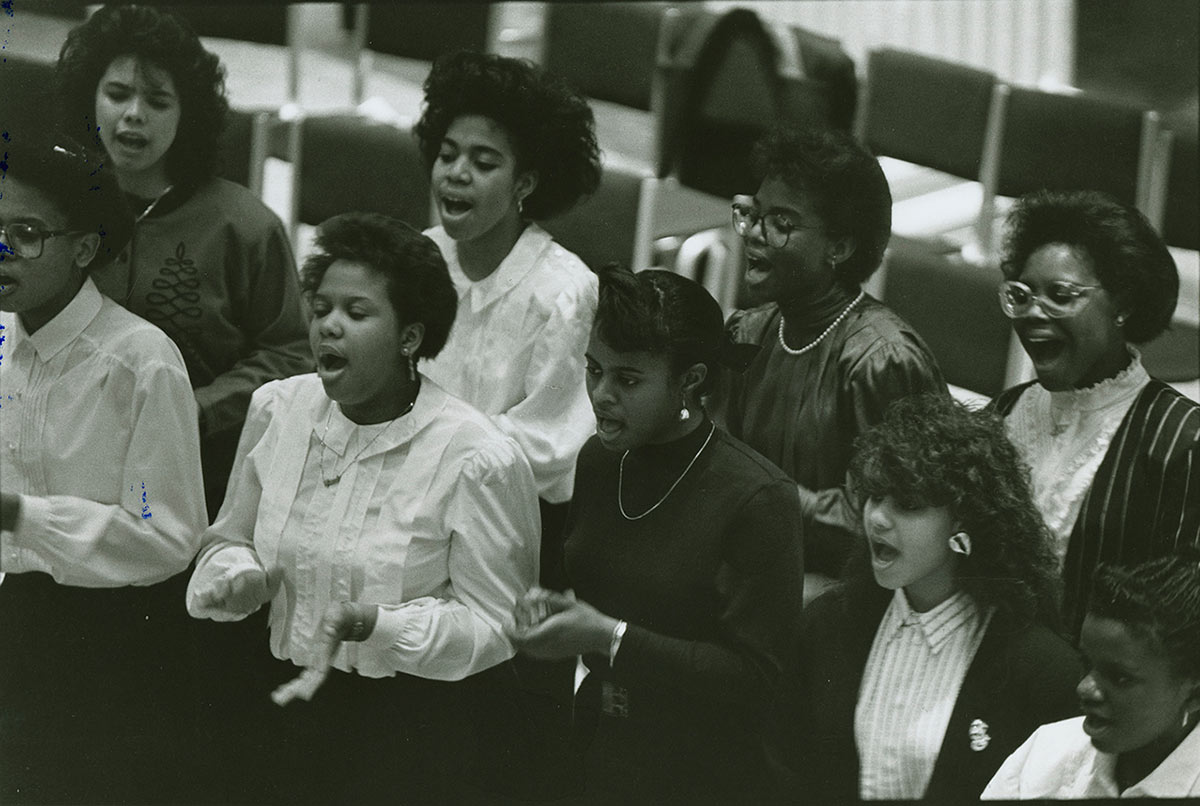 Women students of color sing in a performance